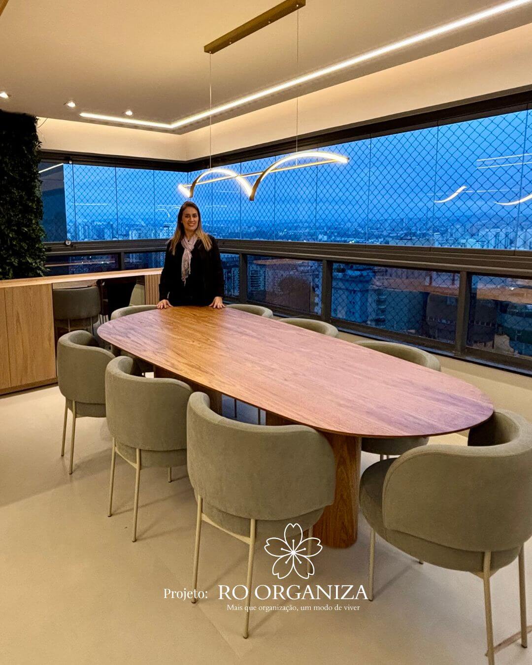 Rosangela em sala de jantar moderna com mesa de madeira e vista da cidade